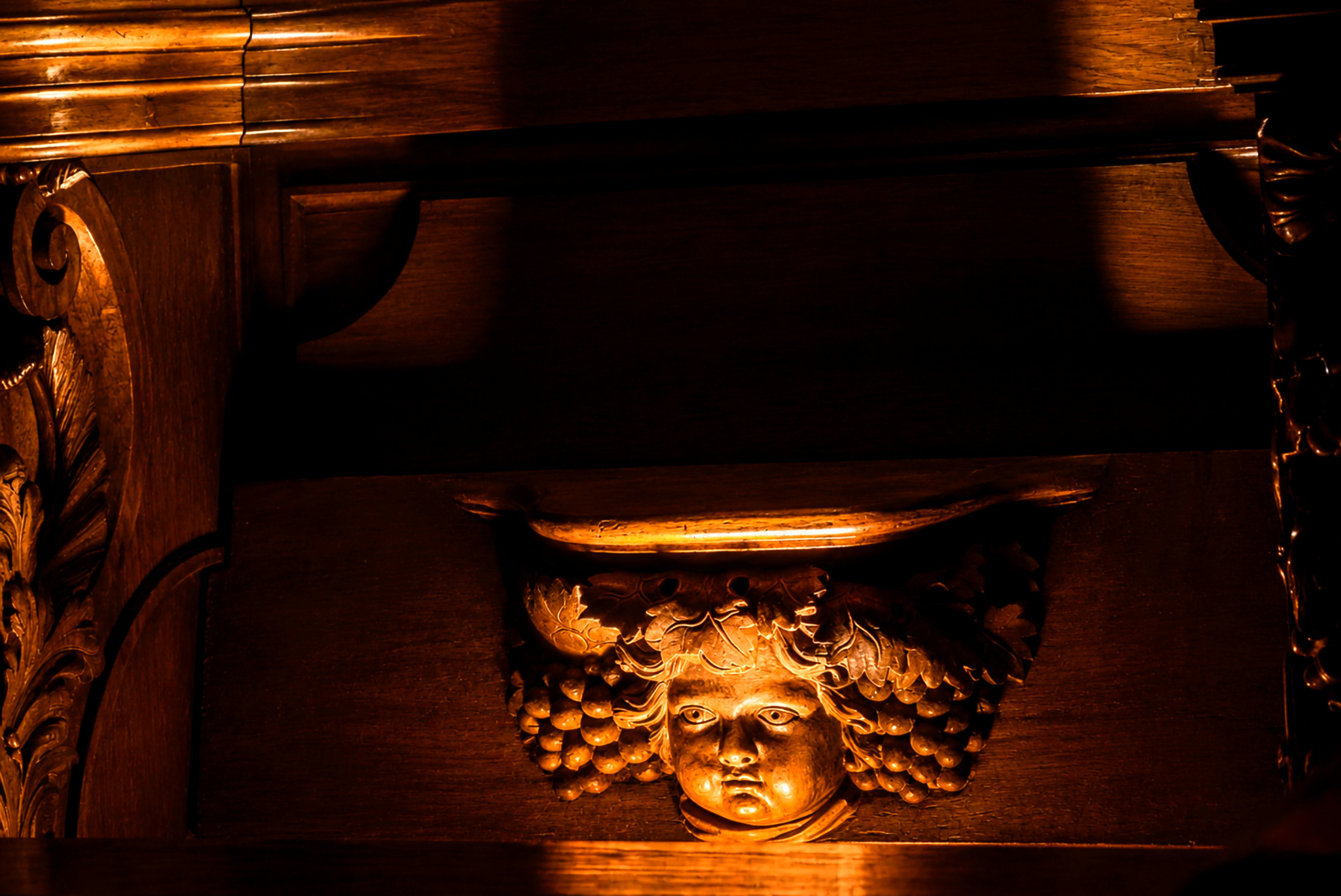 Visage sculpté dans les boiseries de Bassac éclairé d'une lumière dorée